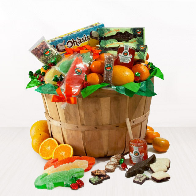 Wooden grove basket filled with assorted snacks and fruits on a white background